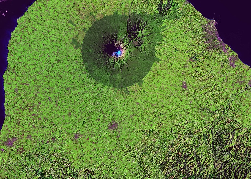 "A nearly perfect circle of forest delineates the boundary of Egmont National Park in New Zealand. Snow-capped Mount Taranaki marks the center of the park, which is surrounded by green farmland." - USGS